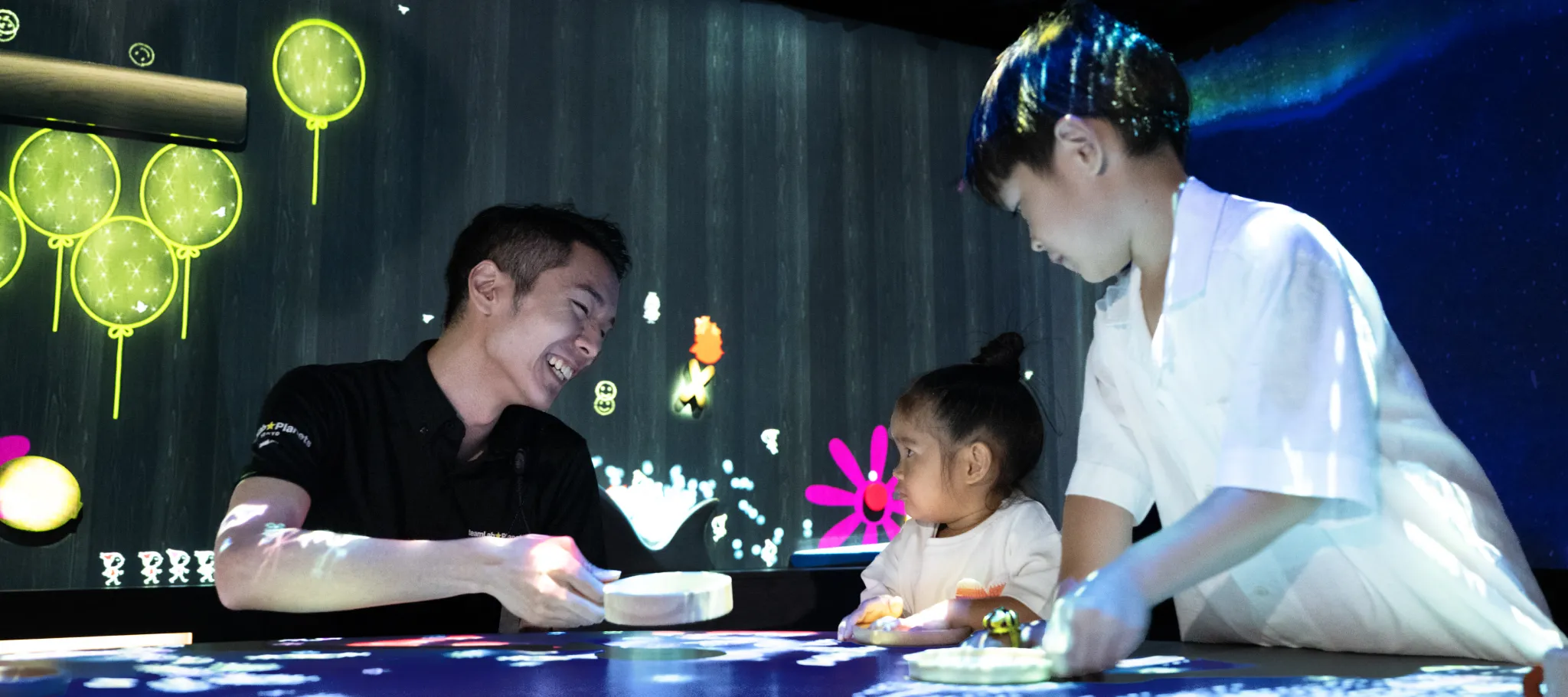 A staff member assisting guests at the teamLab Planets shop. The shift-based system offers a flexible working environment, with students and part-time workers also actively involved.